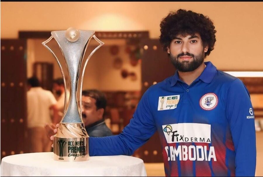 Cambodia player standing beside the ACC Men's Premier Cup trophy